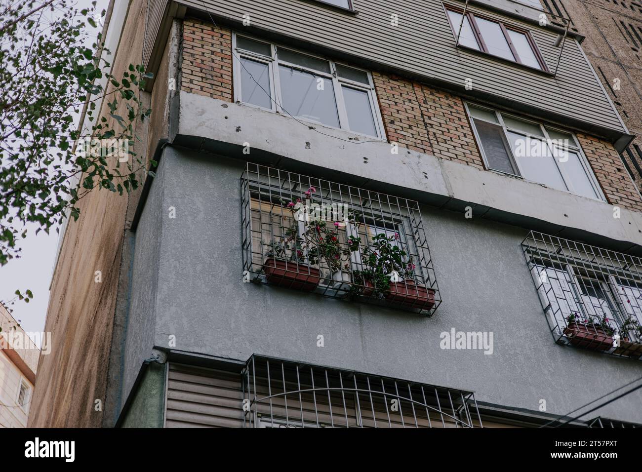 Edificio residenziale sovietico a piu' piani con diversi tipi di balconi. Finestre con bar e fiori in pentole. Angolo di una casa costruita durante il Foto Stock