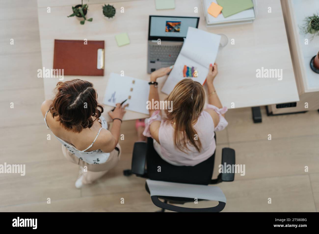 Due donne d'affari che lavorano a un nuovo progetto in ufficio, analizzano rapporti o documenti, discutono dettagli o istruzioni e pianificano. Lavoro di squadra Foto Stock