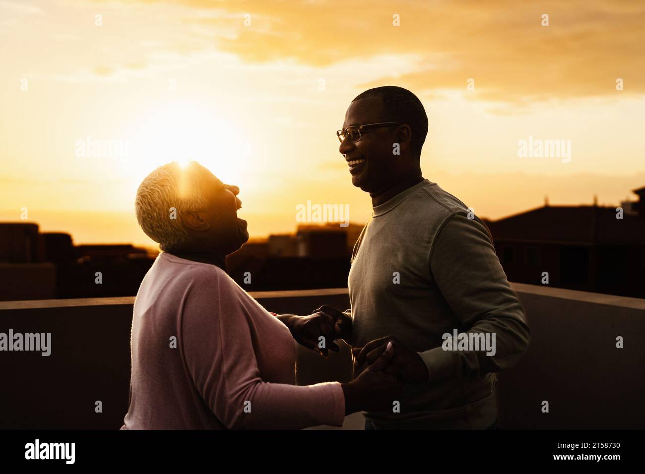 Felice coppia di anziani latini che ha un momento romantico sul tetto all'ora del tramonto - gli anziani amano il concetto Foto Stock