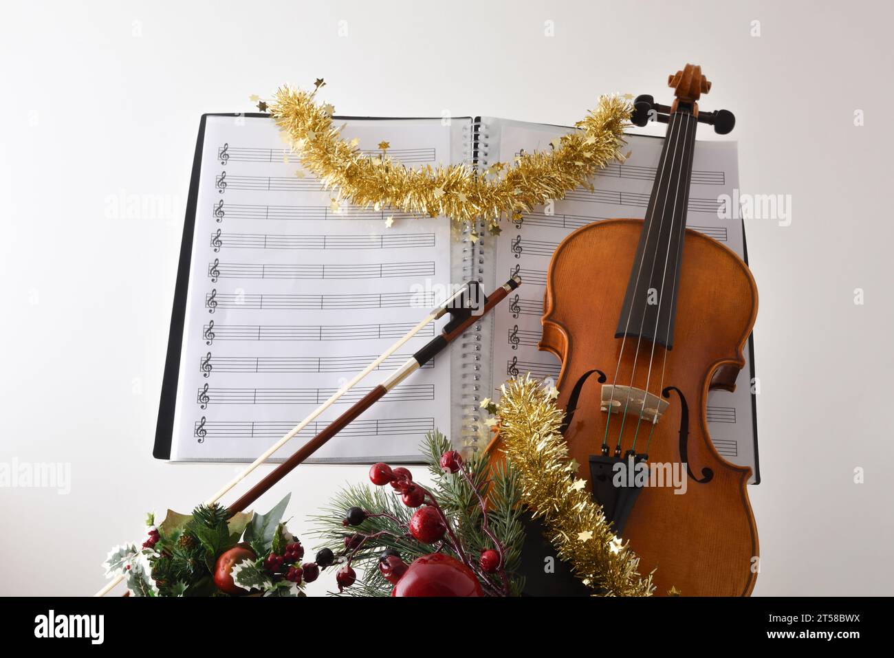 Concetto di musica liutina religiosa natalizia con violino con decorazione natalizia e spartiti musicali con sfondo bianco isolato. Vista frontale. Foto Stock