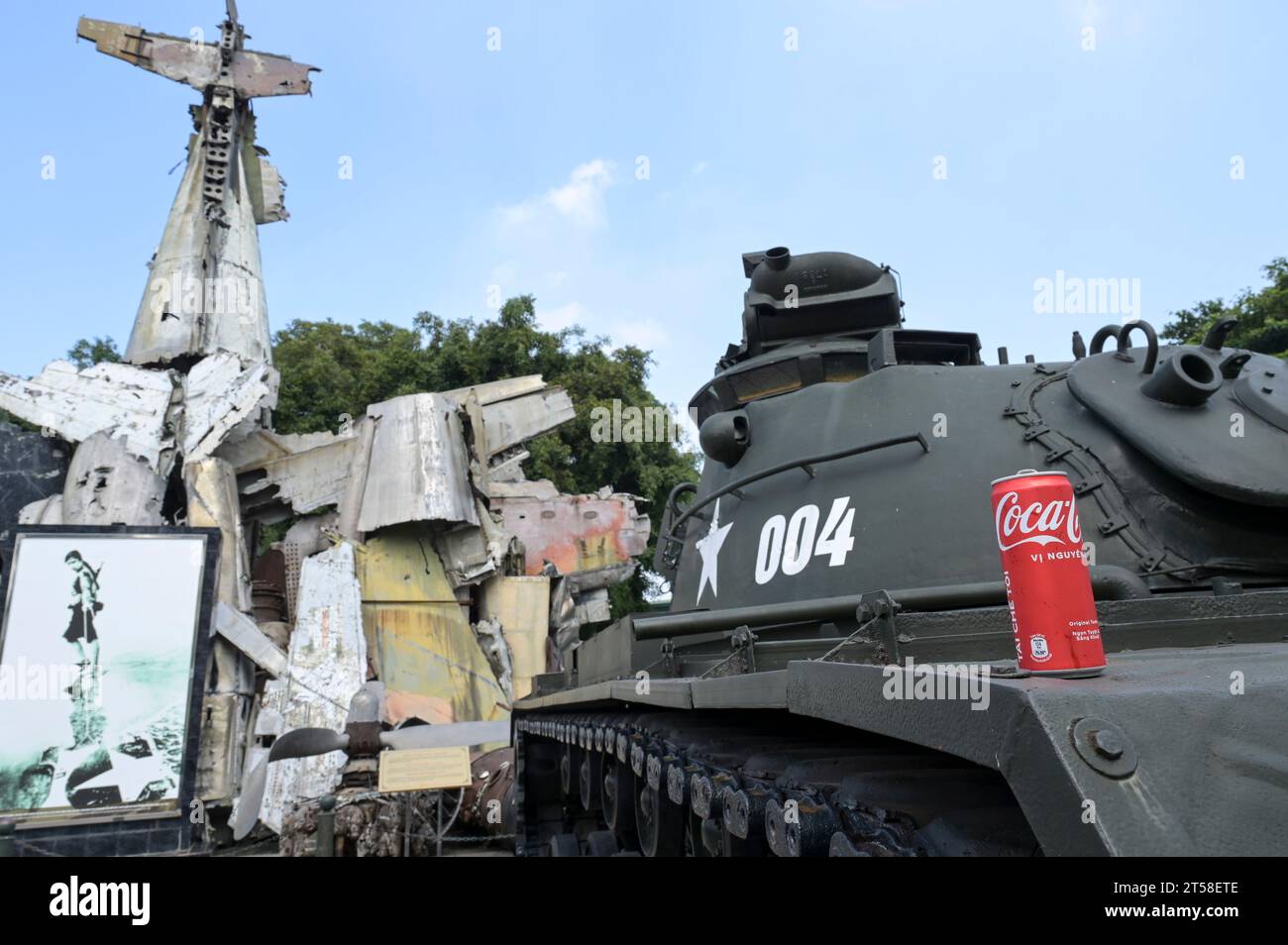 VIETNAM, Hanoi, Museo militare, equipaggiamento militare e rottami di guerra dalla guerra coloniale francese 1946-1954 e la guerra americana in Vietnam 1955 - 1975, carro armato da battaglia americano M-48 Patton e relitto di Grumman F6F Hellcat, un aereo da combattimento americano da portaerei utilizzato dall'esercito coloniale francese, abbattuto in battaglia a Dien Bien Phu 1954 , famosa fotografia o immagine di donna vietnamita che tira un'ala di aerei americani abbattuti, vietnamita Coca Cola CAN Foto Stock