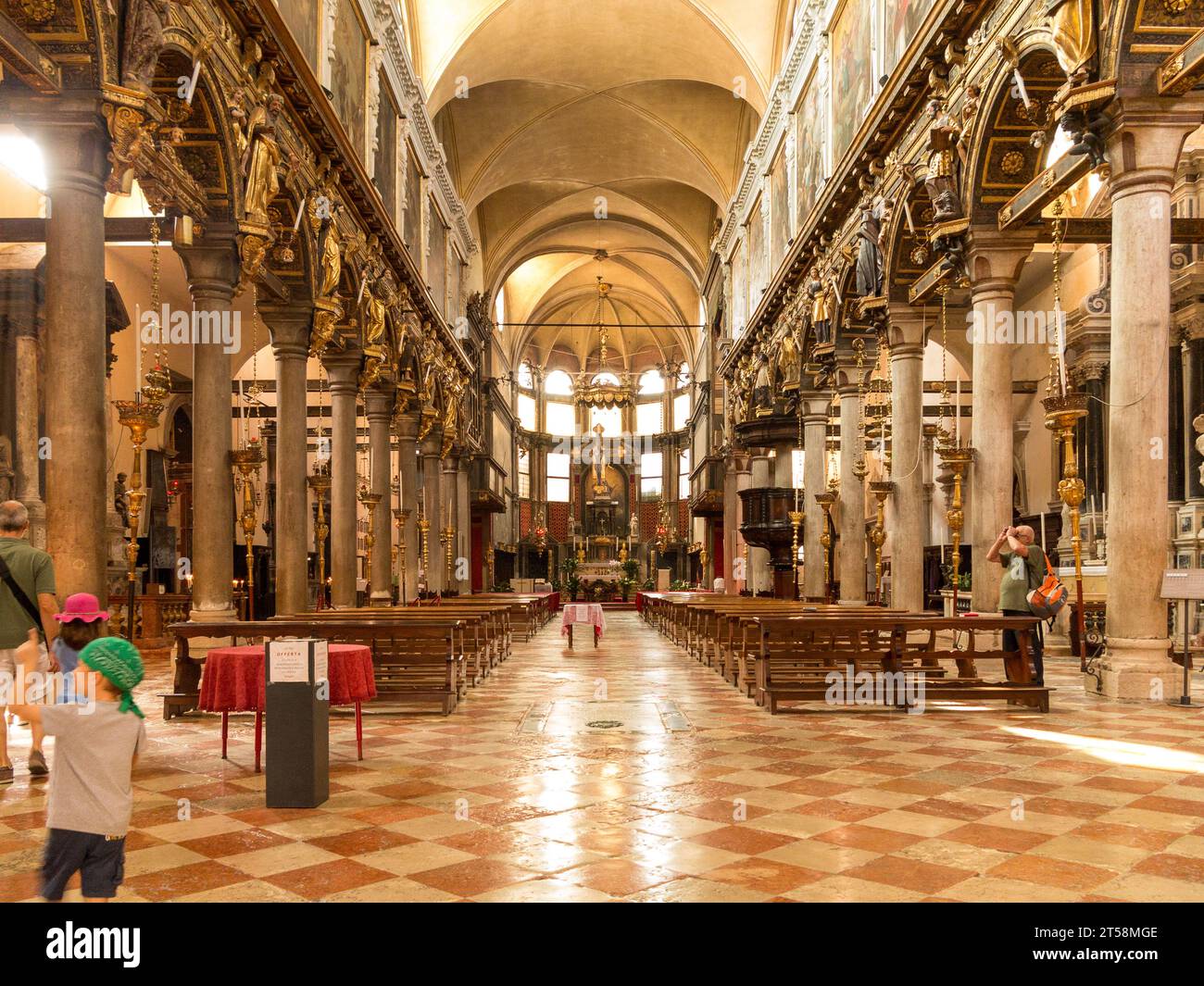 Interno della chiesa di Chiesa Giorgio a Venezia. Quattro turisti ammirano e fotografano il paesaggio. Vista simmetrica dei banchi. colonne e vault. Foto Stock