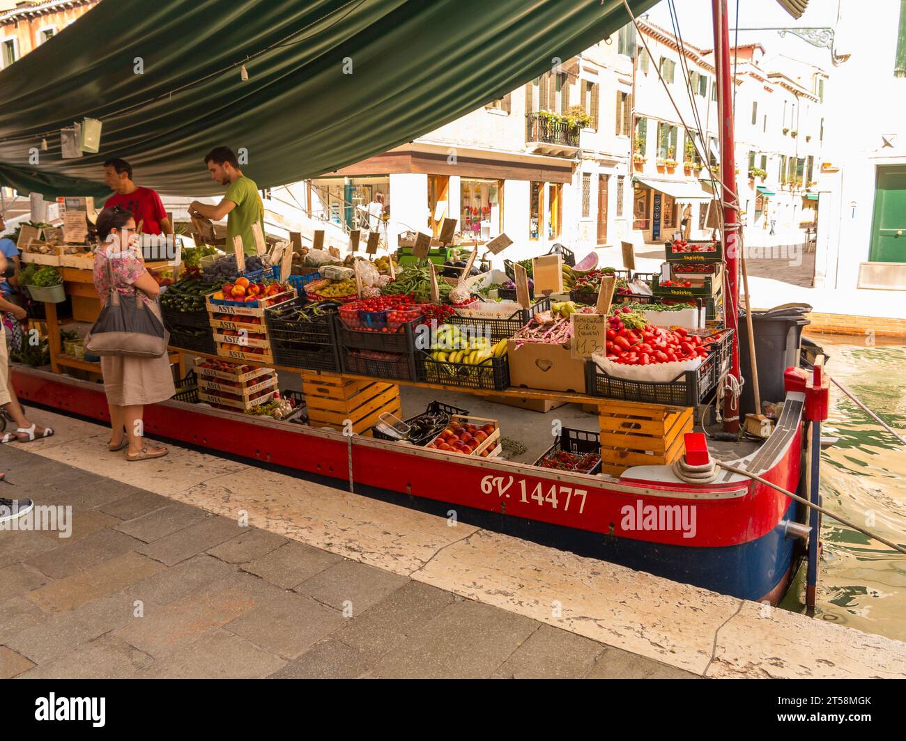 Commerciante di frutta e verdura a Venezia. La sua particolarità è che consegna i suoi prodotti in barca sui canali. Due venditori di imbarcazioni servono i clienti Foto Stock