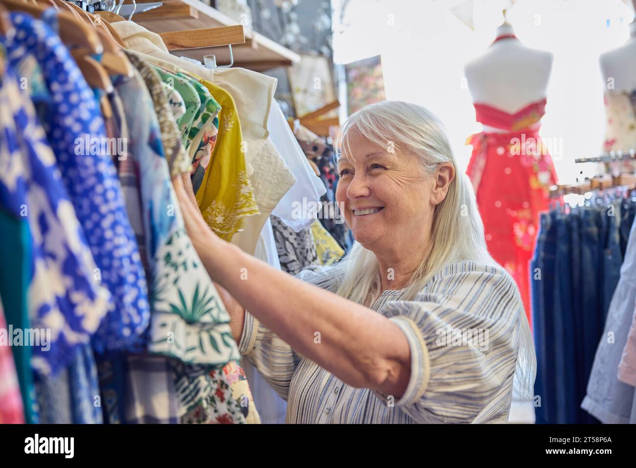 Donna anziana che acquista vestiti sostenibili usati dal negozio di beneficenza di seconda mano o dal negozio Thrift Foto Stock