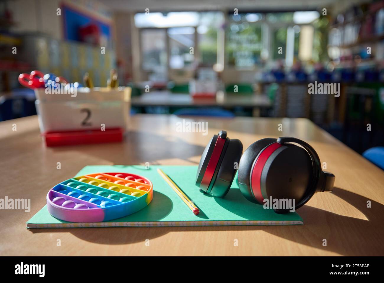 Cuffie o cuffie protettive e giocattolo Fidget per aiutare i bambini con ASD o autismo sul tavolo in classe scolastica Foto Stock