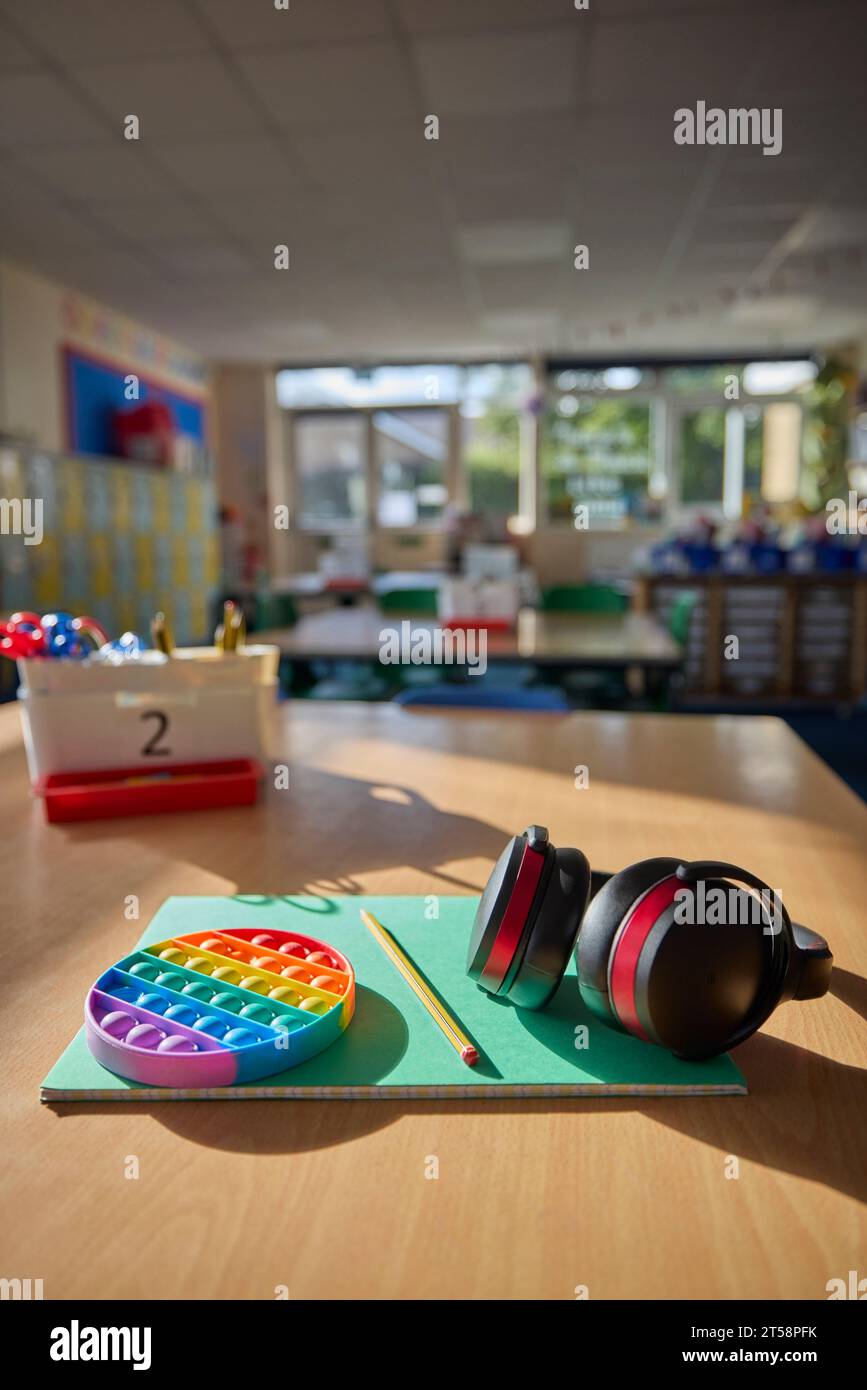 Cuffie o cuffie protettive e giocattolo Fidget per aiutare i bambini con ASD o autismo sul tavolo in classe scolastica Foto Stock