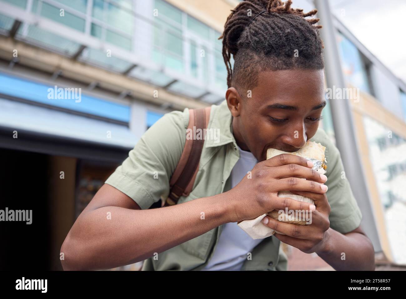 Young Man che mangia Burrito presso il chiosco all'aperto Takeaway Street Food Stall Foto Stock