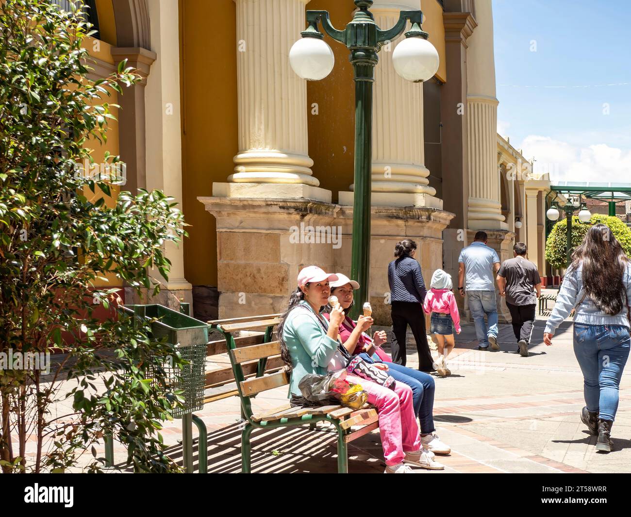 due giovani donne che mangiano un gelato sedute su una panchina. Tunja, Boyacá, Colombia, Sud America Foto Stock