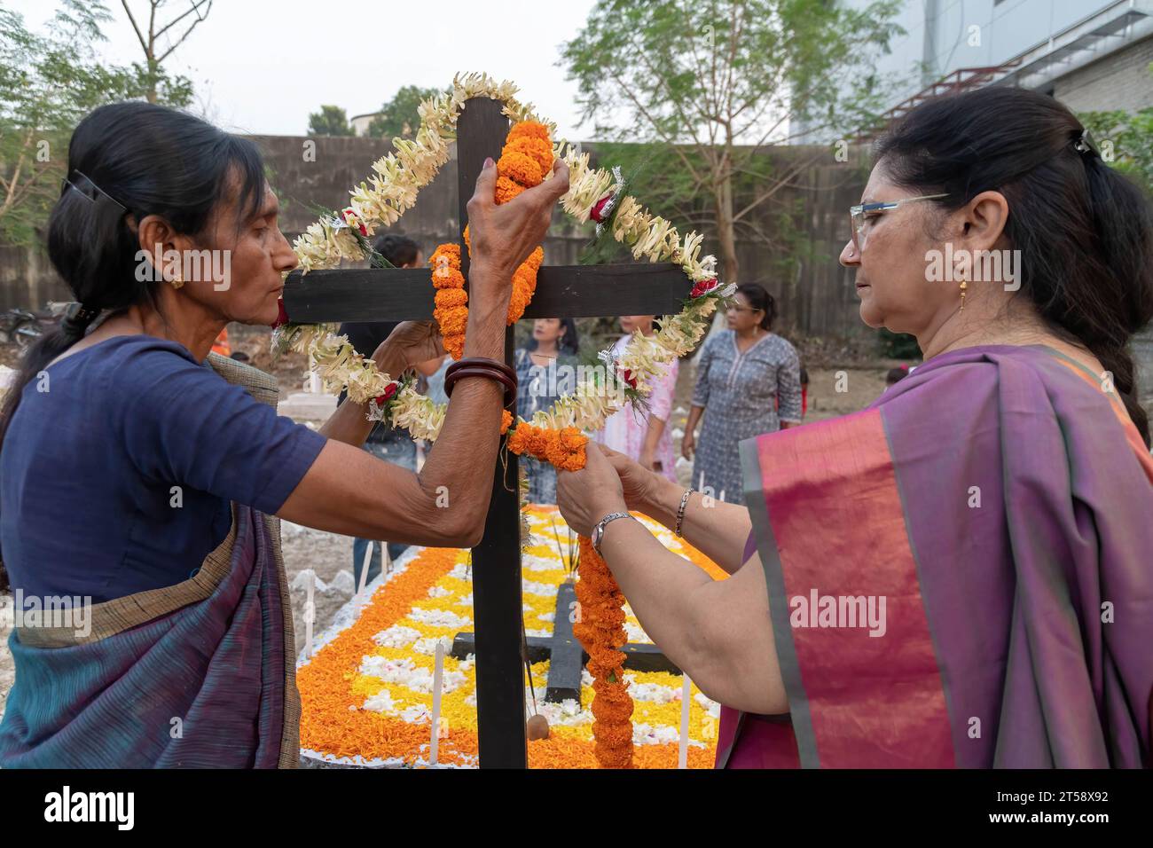 Kolkata, India. 2 novembre 2023. Due donne cattoliche indiane decorano la croce per i loro parenti defunti durante la commemorazione della giornata delle anime in un cimitero. I cattolici indiani accendono le candele per i loro parenti defunti durante la commemorazione di All Souls' Day in un cimitero, in questo giorno i cattolici pregano per i morti. Credito: SOPA Images Limited/Alamy Live News Foto Stock