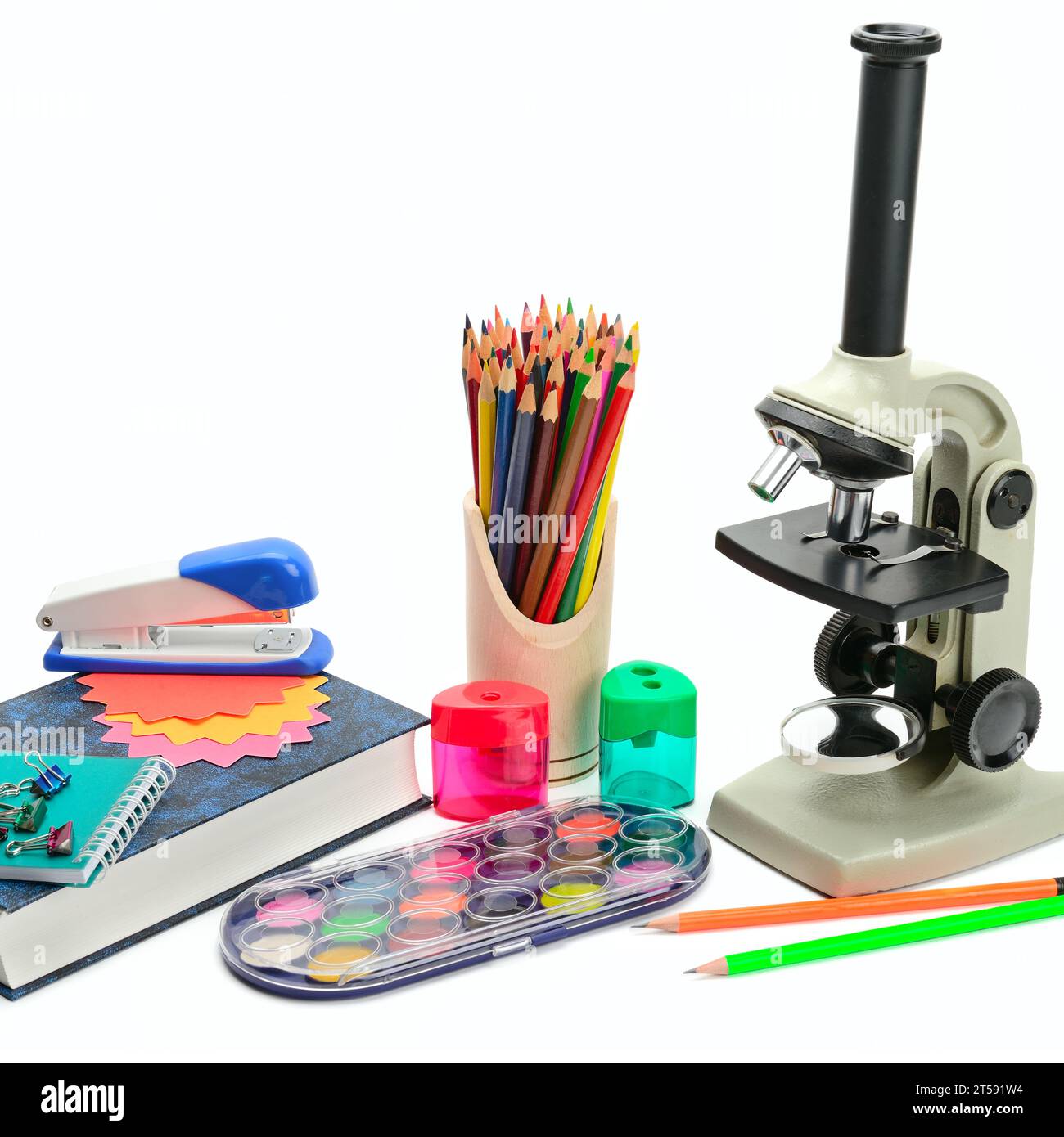 Microscopio da laboratorio, manuale e altri materiali scolastici isolati su sfondo bianco. Vendita scolastica. Foto Stock