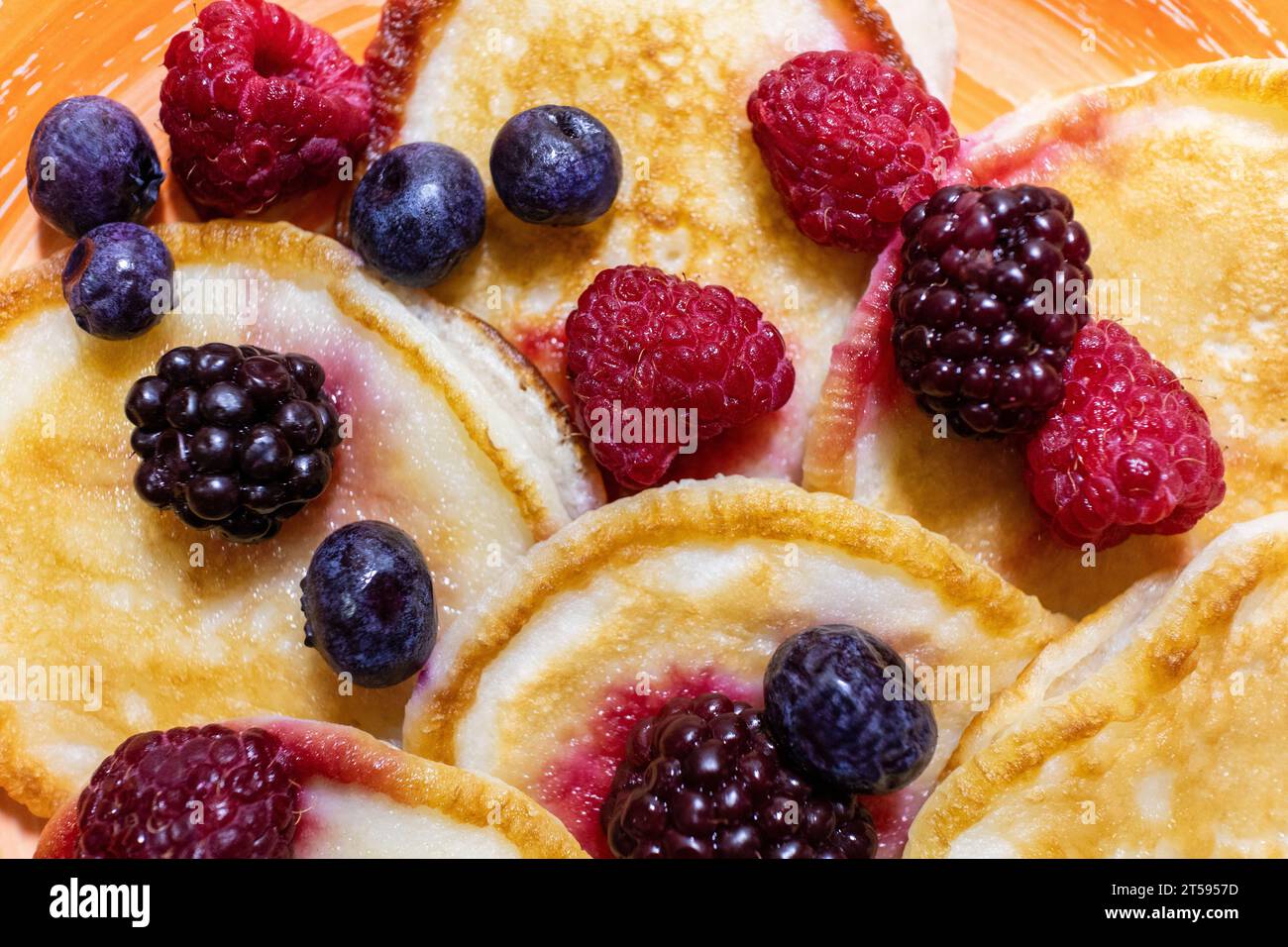 Primi piani deliziosi pancake, con mirtilli freschi, lamponi e more, lo sfondo di un delizioso dessert Foto Stock