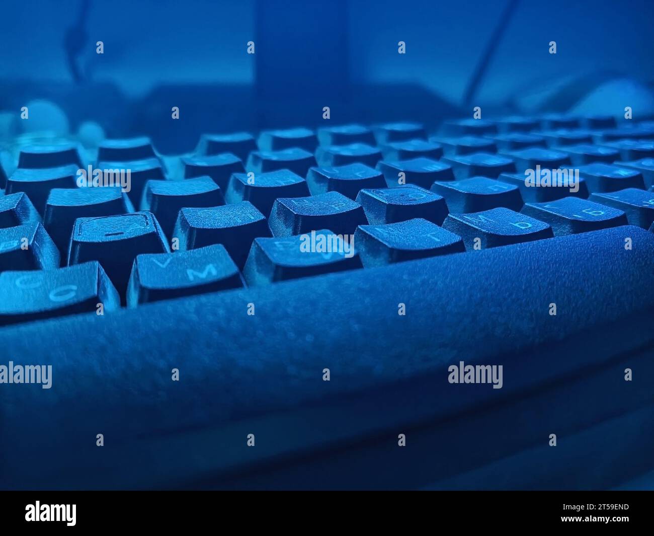 Dettaglio della tastiera in condizioni di scarsa illuminazione con sfumature blu, primo piano Foto Stock