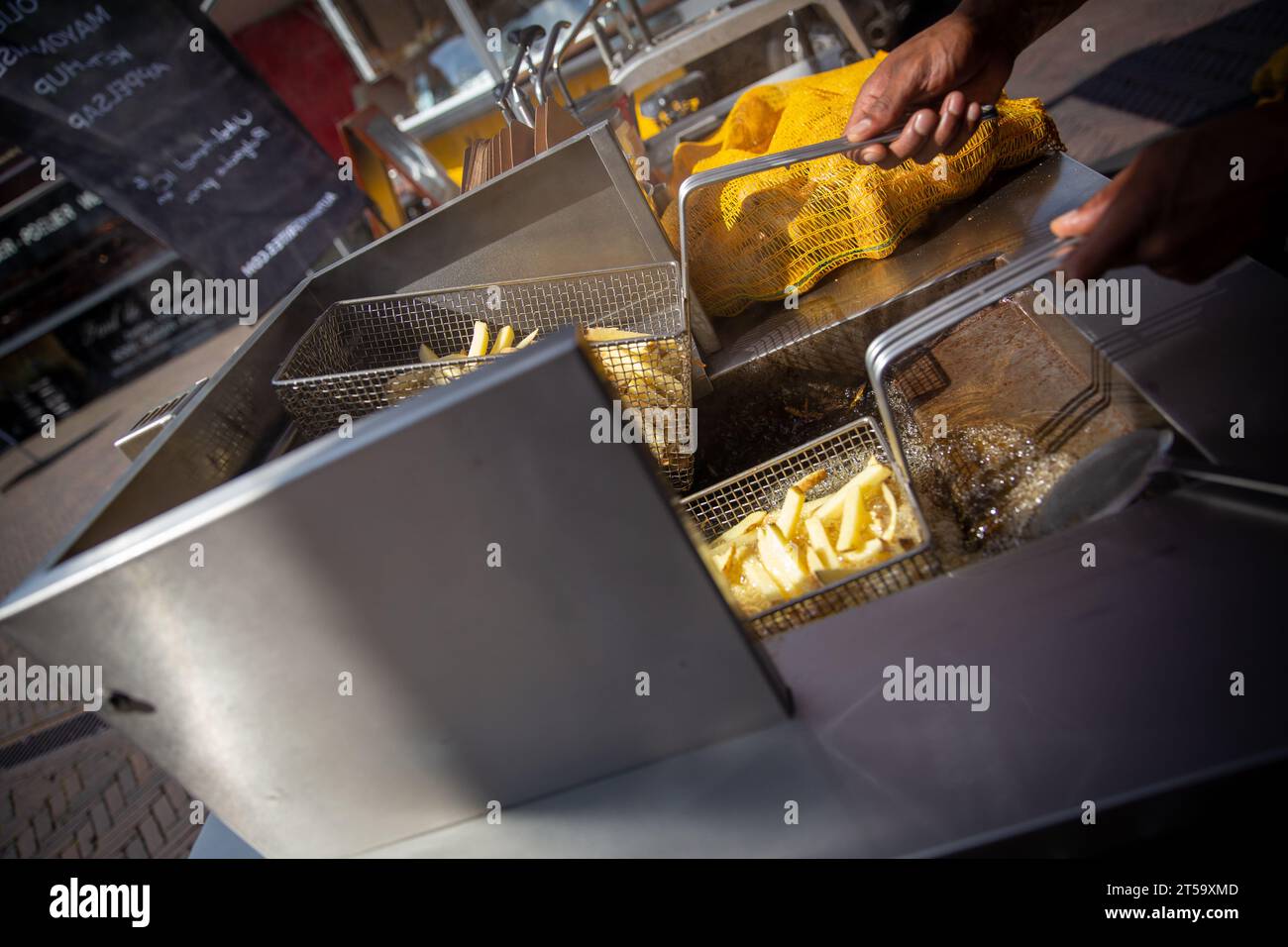 Friggere patatine fritte appena tagliate in un mercato su cui fare uno spuntino Foto Stock