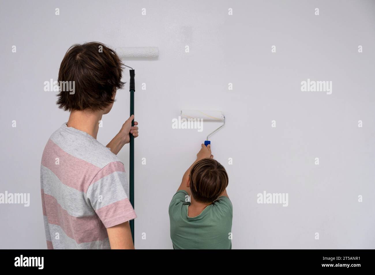 i bambini dipingono il muro con un rullo. gli adolescenti trascorrono del tempo insieme aiutando a riparare Foto Stock