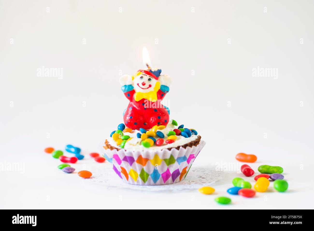 Tazza di torta decorativa con sfondo bianco candela pagliaccio illuminato Foto Stock
