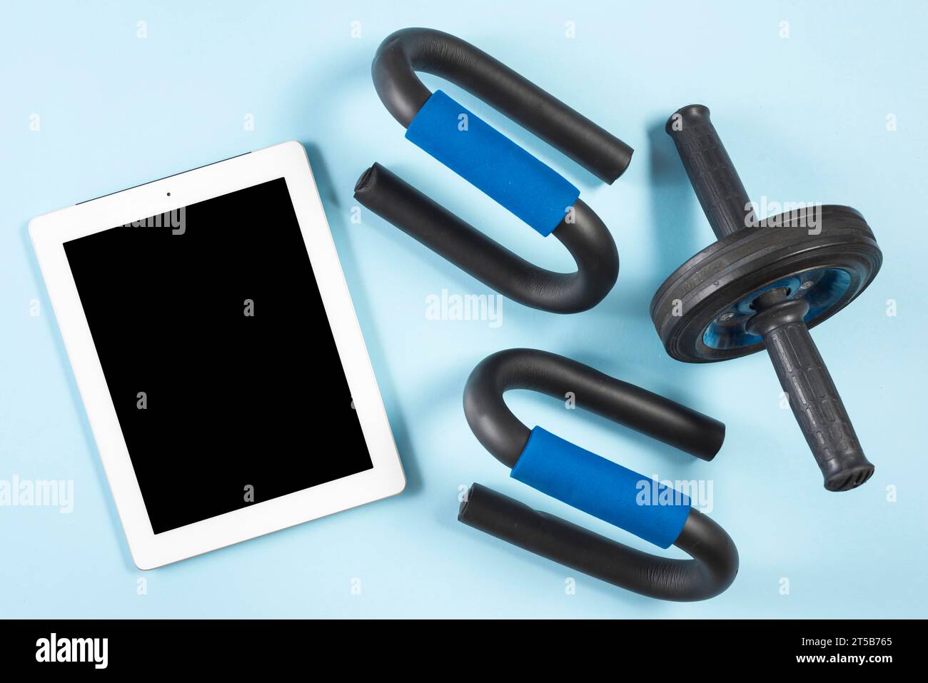 Tablet digitale con vista rialzata con rullo fitness, barra di spinta su sfondo blu Foto Stock