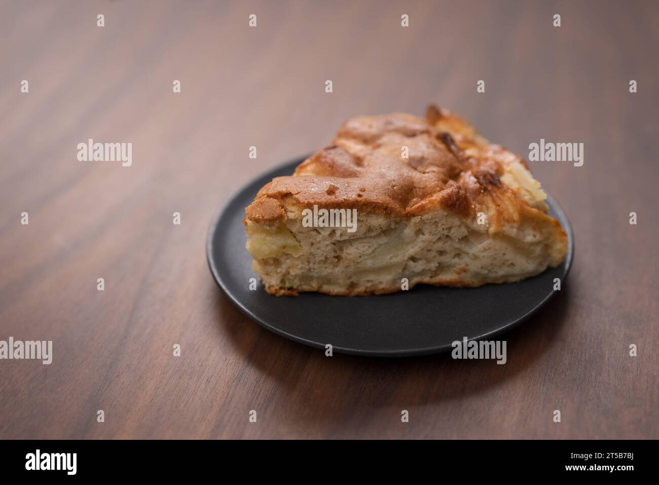 Un pezzo di torta di mele charlotte su un piattino su un tavolo di noci, fuoco poco profondo Foto Stock