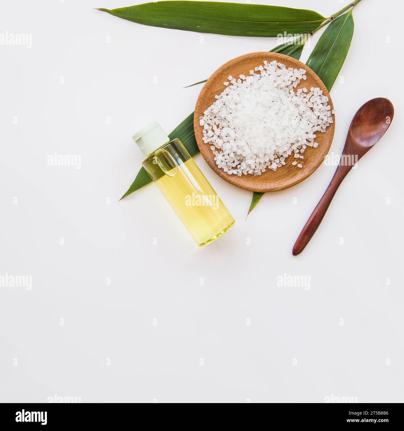 Foglie di sale, cucchiaio di olio essenziale spruzzato in bottiglia, sfondo bianco Foto Stock
