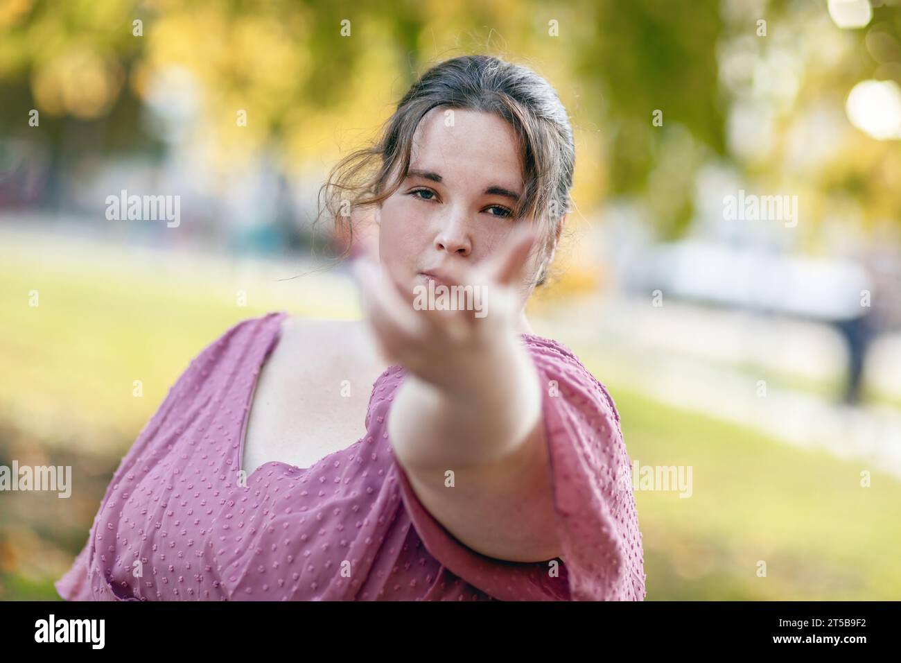 Ritratto di una giovane donna in taglia più grande che indossa un abito in un parco in una città Foto Stock