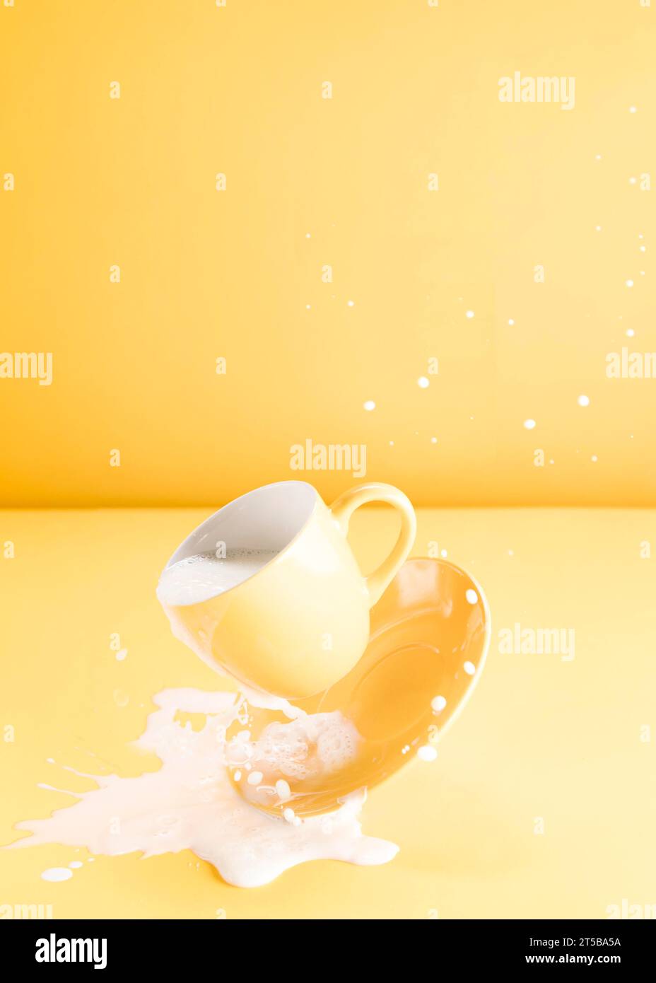 Tazza gialla galleggiante con versamento di latte Foto Stock