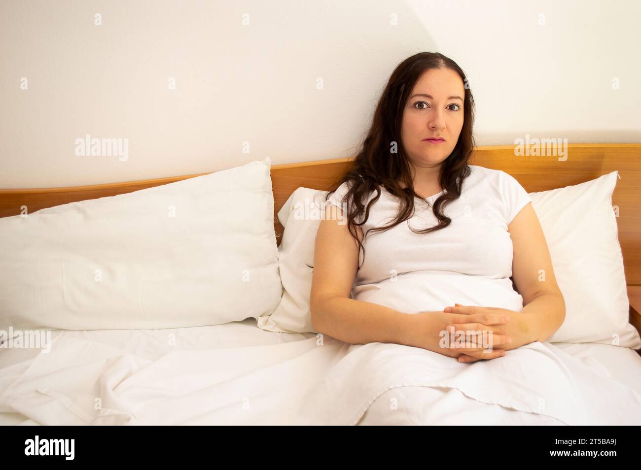 Colpo di donna sdraiata a letto, ignorata e abbandonata. Donna sola nel suo letto con spazio per le copie. Foto Stock