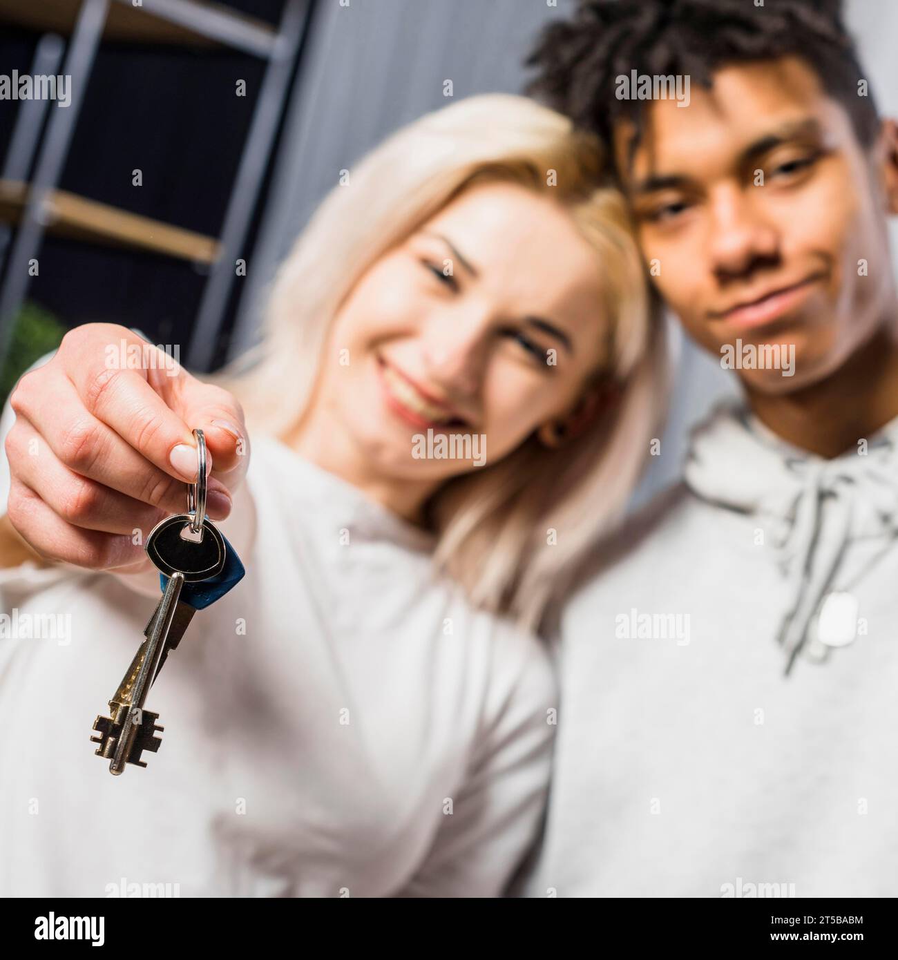 Fidanzata con il suo ragazzo che mostra la chiave di casa verso la telecamera Foto Stock
