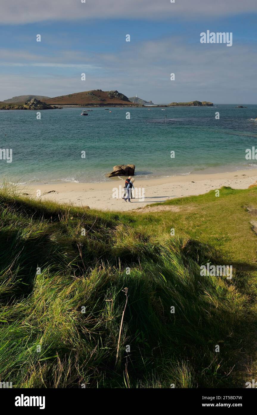 Coppia anziana che cammina lungo Lawrence's Bay. St Martin's, Isles of Scilly, Cornovaglia, Inghilterra. REGNO UNITO Foto Stock