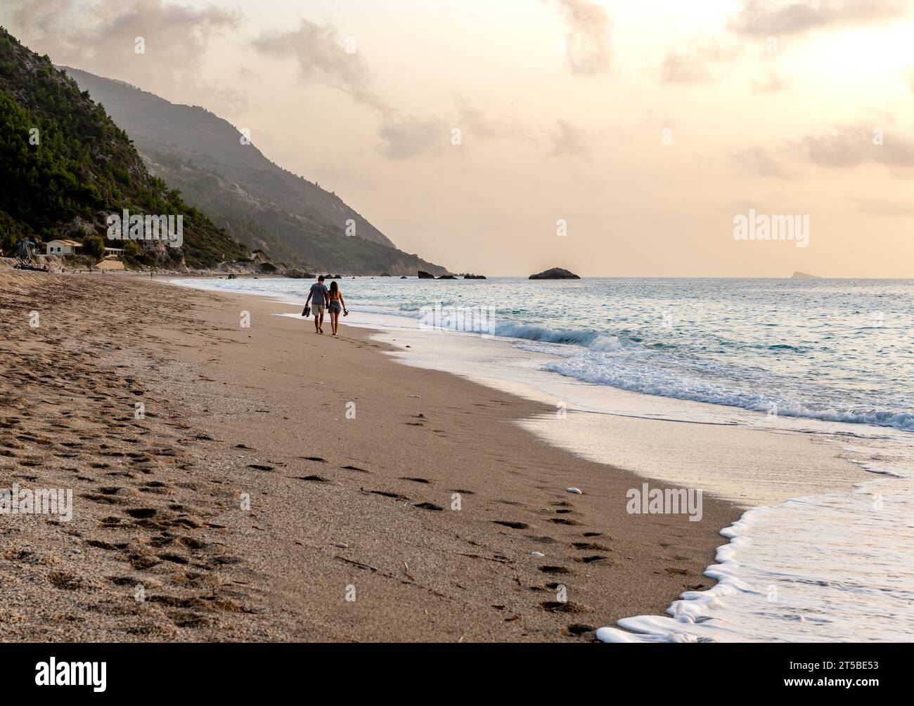 Una coppia in vacanza passeggiando su una bella e lunga spiaggia sabbiosa. Foto Stock