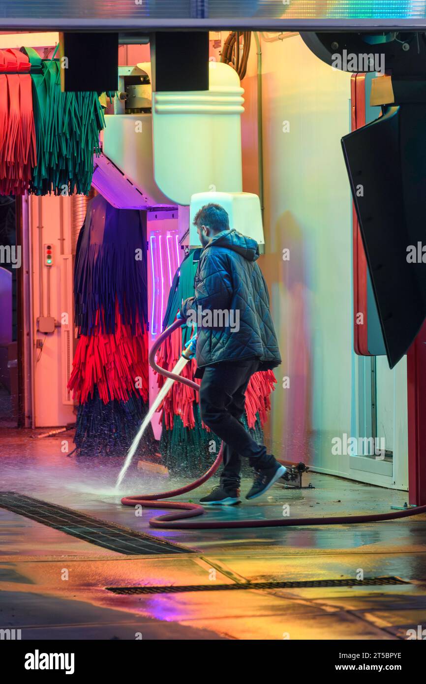 L'addetto alla manutenzione aspira con acqua l'interno di un autolavaggio automatico Foto Stock