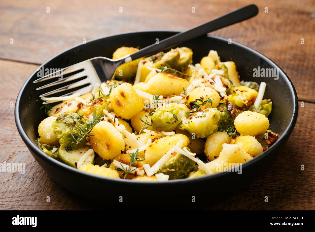 Gnocchi arrostiti e cavoletti di Bruxelles in padella con formaggio vegan grattugiato. Foto Stock