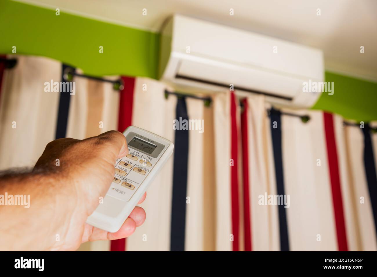 La mano di un uomo che afferra e manipola il telecomando del condizionatore d'aria domestico. Foto Stock