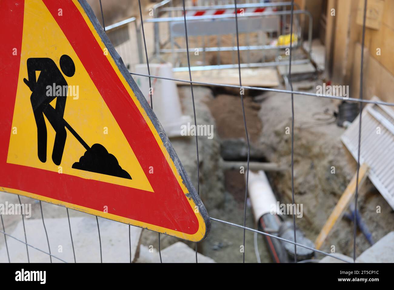 cartello stradale con disegno di una terra di lavoro che si stappa vicino al cantiere stradale in città Foto Stock