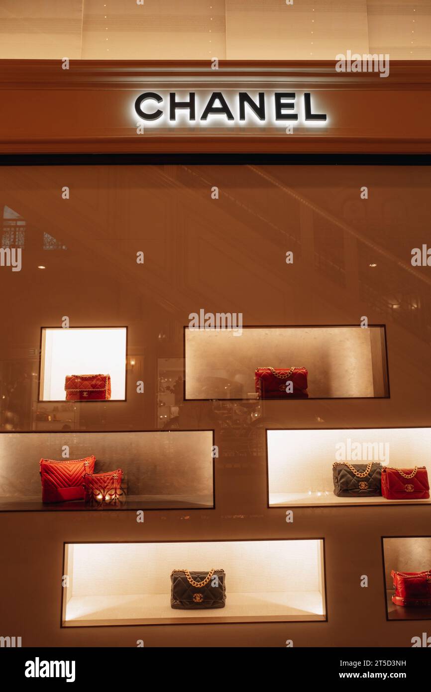 Eleganti borse Chanel femminili color arancione rosso e nero con catena dorata nella finestra di un negozio di lusso. Chanel è un marchio di alta moda fondato da Coco C. Foto Stock