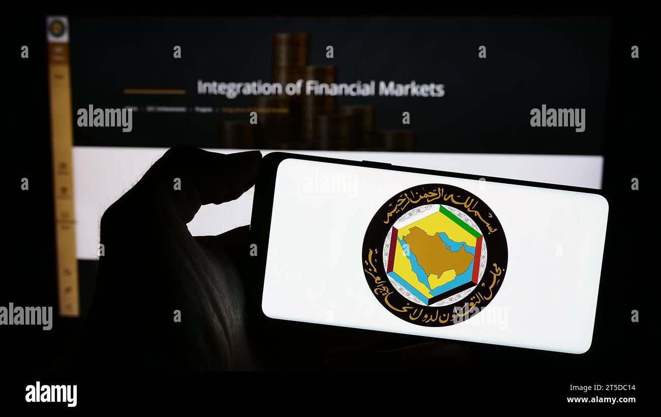Persona in possesso di un cellulare con il logo del Consiglio di cooperazione del Golfo dell'unione araba (CCG) davanti alla pagina web. Concentrarsi sul display del telefono. Foto Stock