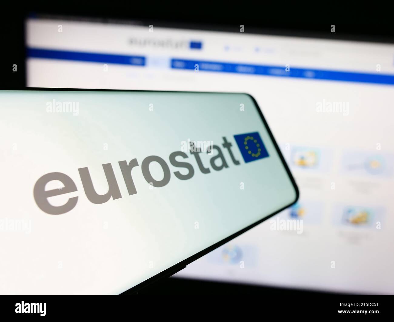 Telefono cellulare con logo dell'Istituto europeo di statistica Eurostat davanti al sito web delle imprese. Mettere a fuoco il display centrale sinistro del telefono. Foto Stock