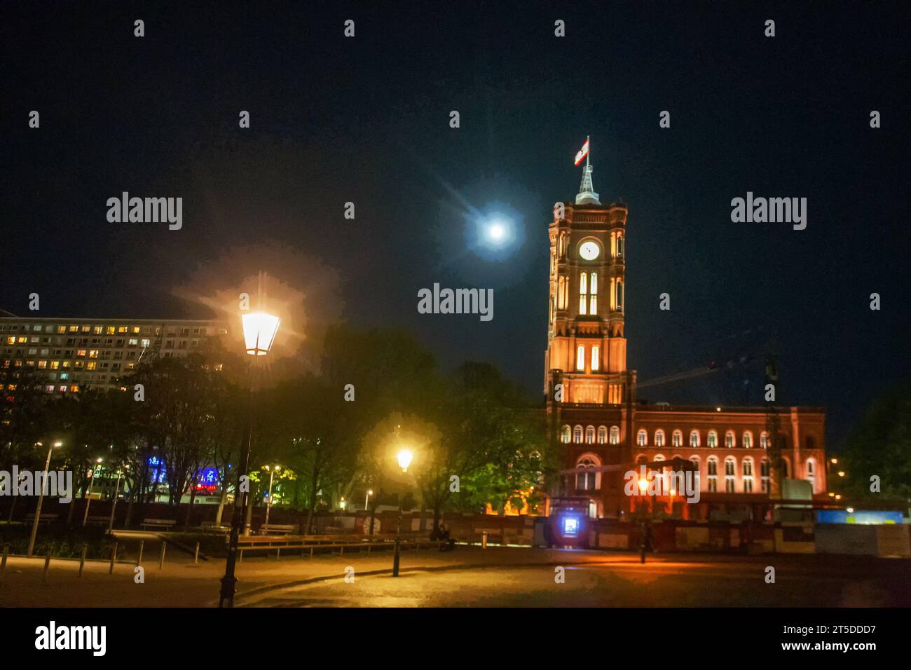 Incredibile torre dell'orologio del municipio di Berlino (Rotes Rathaus) e luna piena dietro. Persone in movimento sfocate. Bandiera del Brandeburgo (o Berlino?) Foto Stock