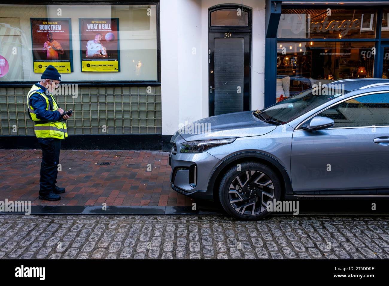 Un addetto al traffico che prende i dettagli di un'auto parcheggiata illegalmente, High Street, Lewes, East Sussex, Regno Unito Foto Stock