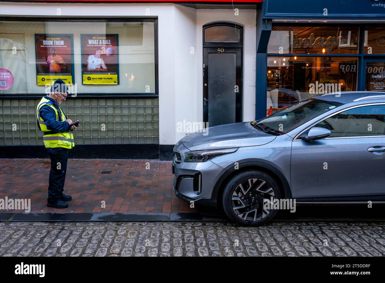 Un addetto al traffico che prende i dettagli di un'auto parcheggiata illegalmente, High Street, Lewes, East Sussex, Regno Unito Foto Stock