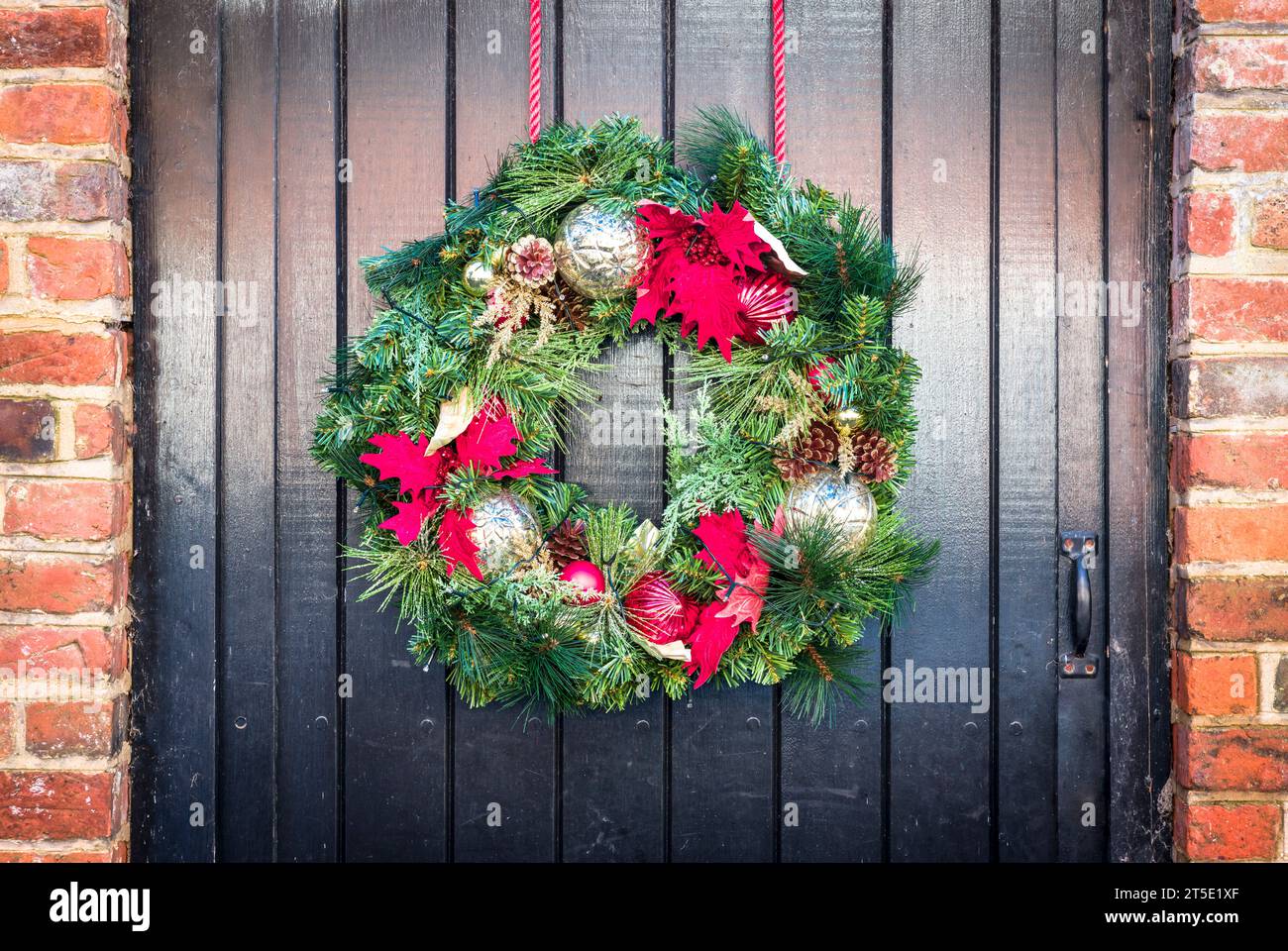 Dettaglio di una corona di Natale su una vecchia porta di legno nera di un cottage, Regno Unito Foto Stock