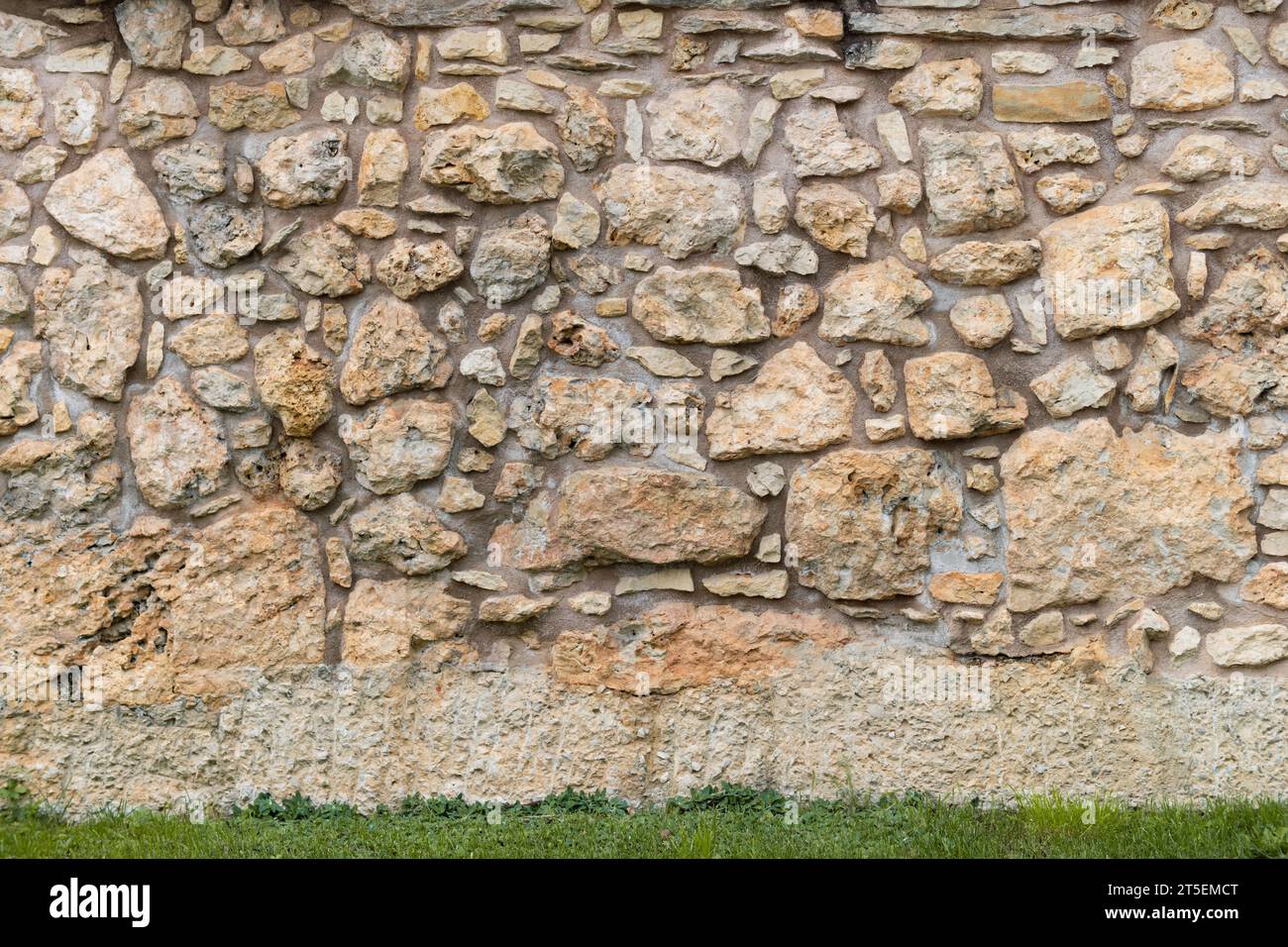 Vecchia trama di sfondo della parete in pietra. L'esterno dell'edificio e' fatto di rocce di dimensioni diverse e cemento nel mezzo. E' stato usato materiale naturale. Foto Stock