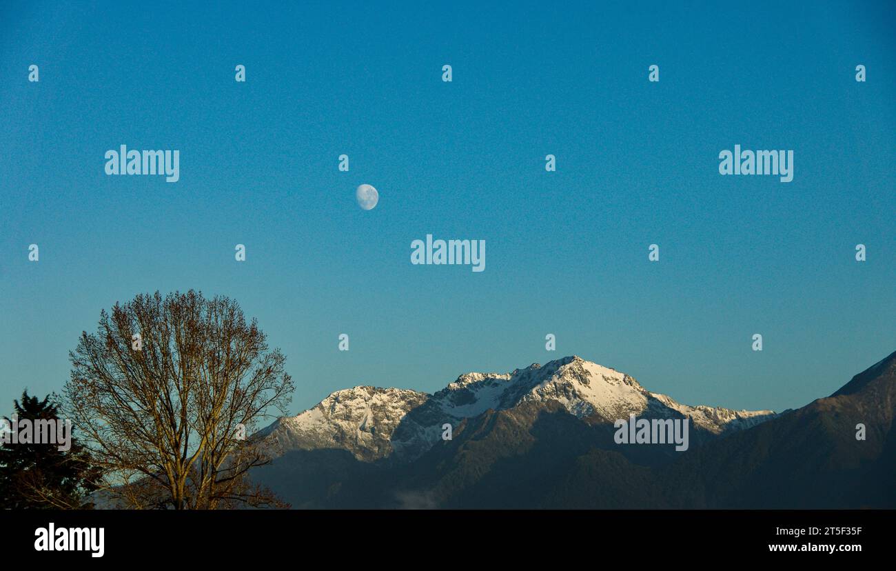 Foto della luna nel pomeriggio che mostra le cime innevate in un parcheggio per roulotte a te Anau, nuova Zelanda Foto Stock