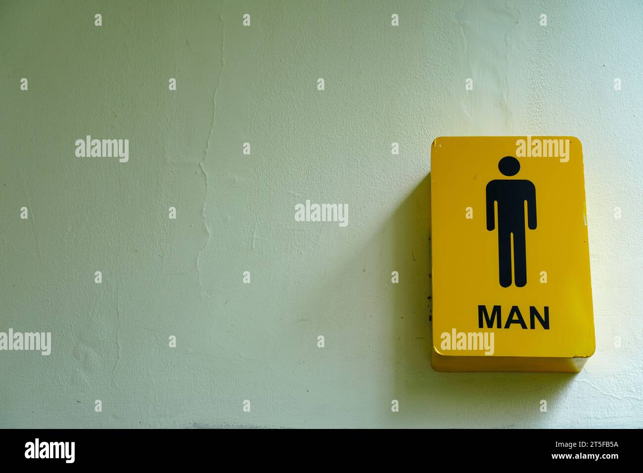 Il simbolo di genere maschile in primo piano adorna una parete bianca pulita con un'eleganza minimalista Foto Stock