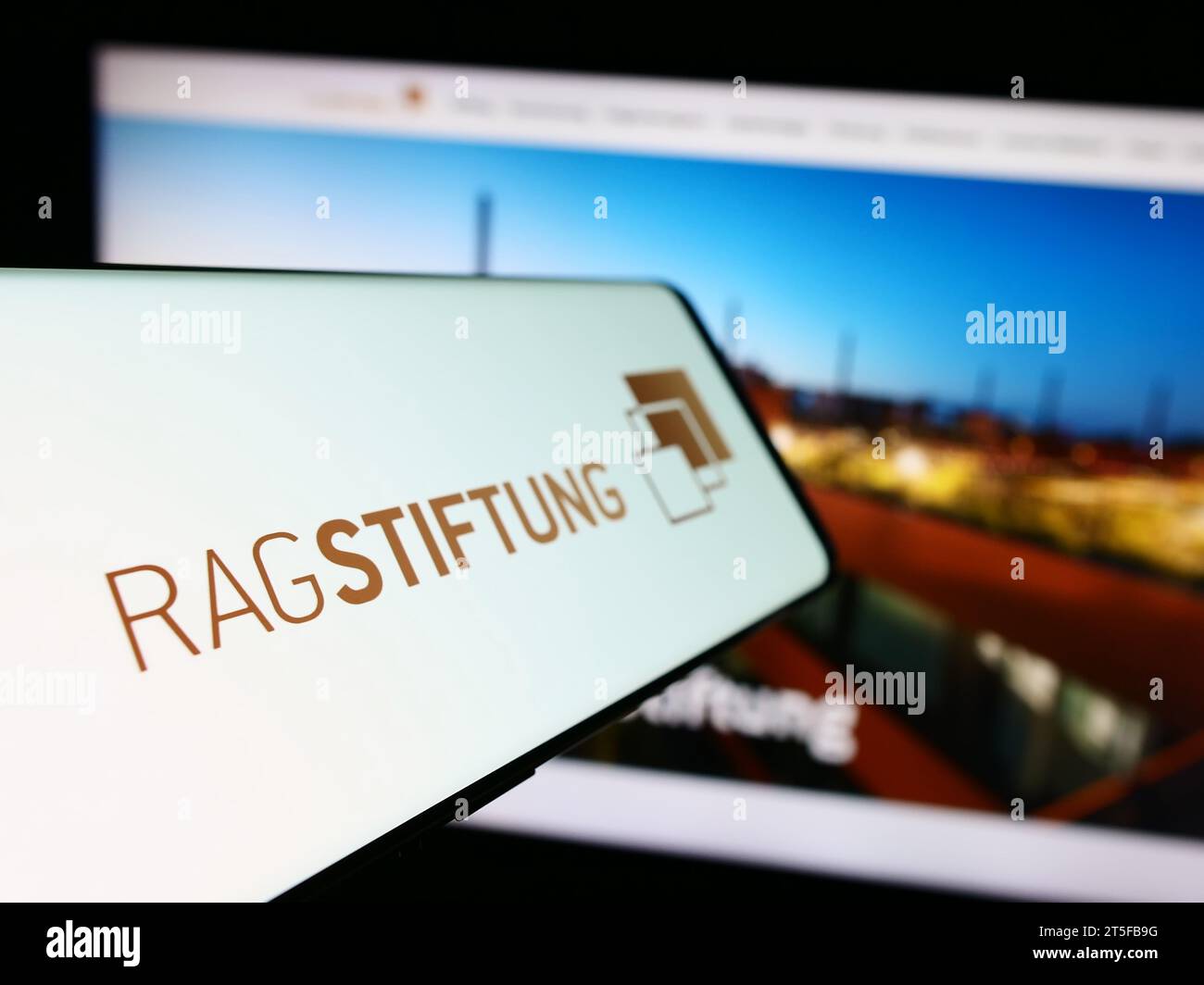 Telefono cellulare con logo della fondazione tedesca RAG-Stiftung davanti al sito web. Mettere a fuoco il display centrale sinistro del telefono. Foto Stock