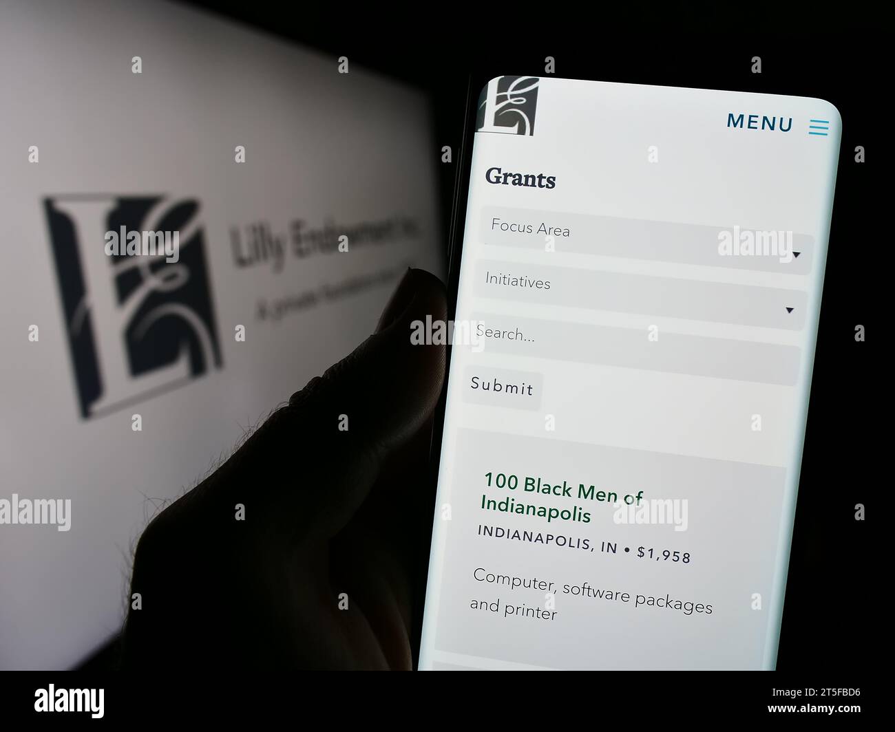 Persona che possiede uno smartphone con il sito Web della fondazione statunitense Lilly Endowment Inc. Davanti al logo. Concentrarsi sul centro del display del telefono. Foto Stock