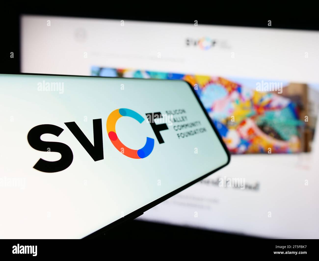Telefono cellulare con logo dell'organizzazione statunitense Silicon Valley Community Foundation (SVCF) davanti al sito Web. Mettere a fuoco il display centrale sinistro del telefono. Foto Stock
