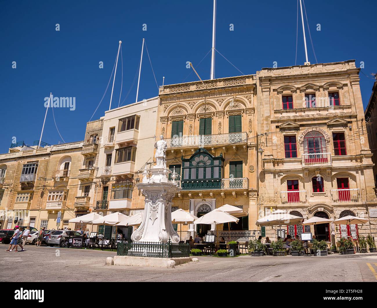 Vittoriosa, Malta - 17 giugno 2023: Ombrelloni con tavoli da bar nella piazza di Vittoriosa sotto gli edifici Foto Stock
