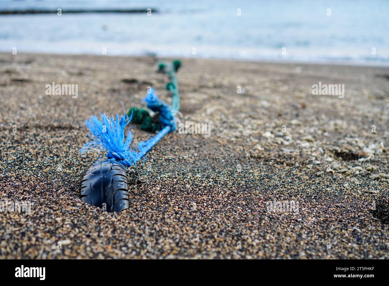 Foto ravvicinata di un'ancora tradizionale della barca con corda e vecchi pneumatici incorporati nella sabbia della spiaggia Foto Stock