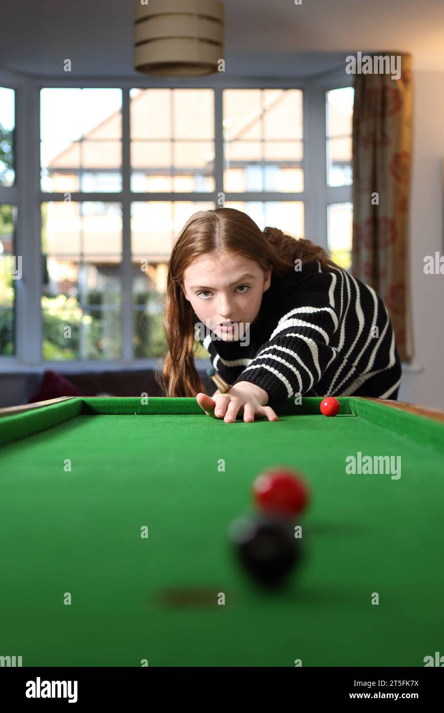 Ragazza adolescente che mira a un tiro in un tradizionale gioco da pub di bagatelle nella sala a casa Foto Stock