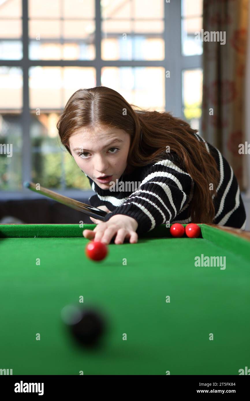 Ragazza adolescente che gioca al tradizionale gioco da pub di bagatelle nella sala a casa, sorprende l'espressione sul suo viso dopo aver colpito la palla Foto Stock