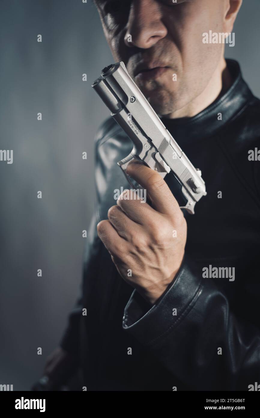 Giacca nera in pelle assassino detective spia assassino assasin con foto ritratto a pistola. Foto Stock